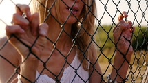 Woman holding onto a wire fence.
