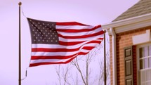 An American Flag outside a red brick building, waving in the wind