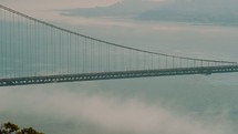 Traffic traveling across the Golden Gate Bridge over the misty ocean water.