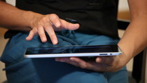 A person sitting down scrolling and searching through their iPad