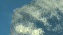 clouds reflecting on the glass windows of a skyscraper 