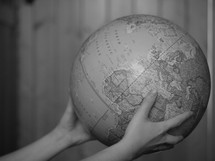 hands holding out a globe 