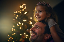 AI generated image. Girl on father’s shoulders wearing crown and enjoying Christmas magic next to the Christmas tree