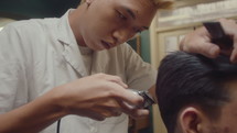 Asian Barber Trimming Hair of Client with Hair Clippers