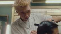 Asian Barber Cutting Hair of Man in Barbershop