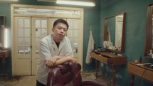 Young Asian Barber Posing on Camera in the Hairdressing Salon
