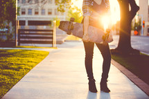 a young woman standing on a sidewalk holding a skateboard 
