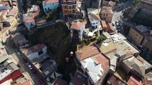 Aerial shot drone orbits to left around funicular as funicular cars are going up and down on hill in coastal city