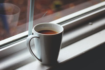 coffee mug in a window sill 
