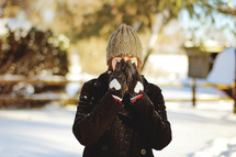 woman standing in snow hiding her face 