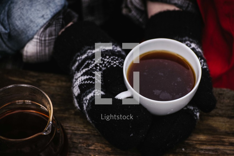 hands in mittens holding a coffee cup 