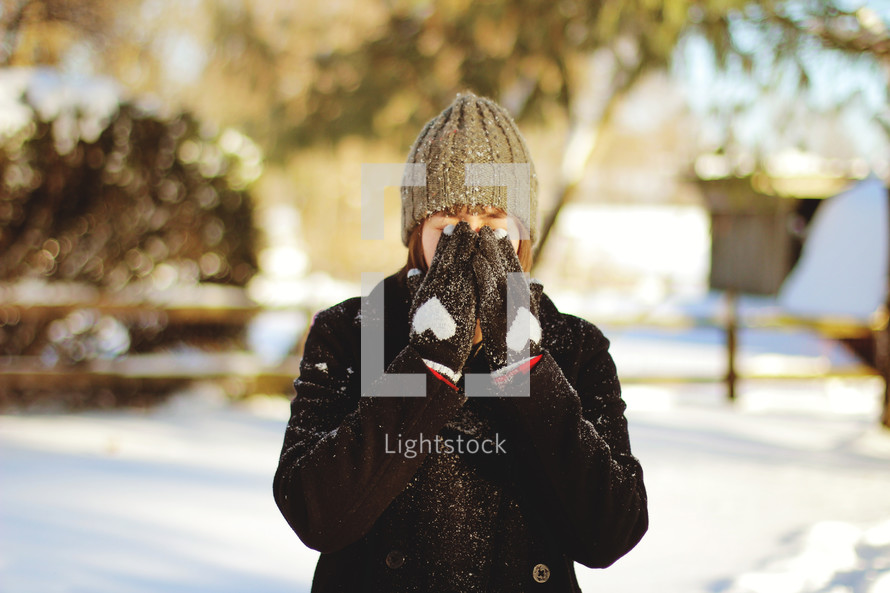 woman standing in snow hiding her face 