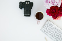 camera, computer keyboard, mug, and flowers on a white background 