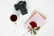 camera, red rose, mug, pencil, and paper on a white background 