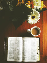 gerber daisies, coffee mug, and an open Bible 