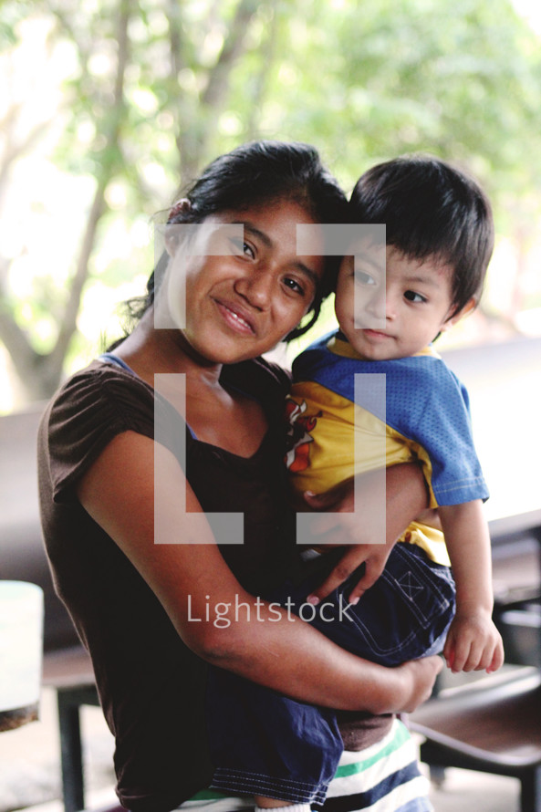 a smiling mother in Guatemala holding her toddler son 