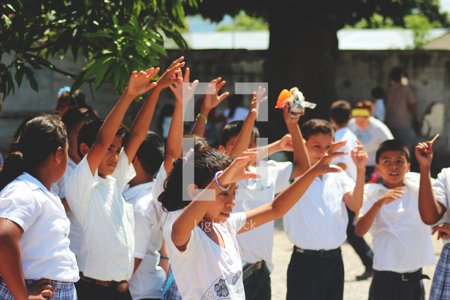 school children in Guatemala with theirs hands up 
