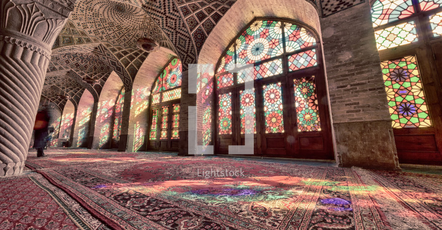 colorful light from stained glass windows on carpets in a mosque 