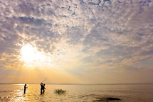 Children wading and fishing during a sunrise