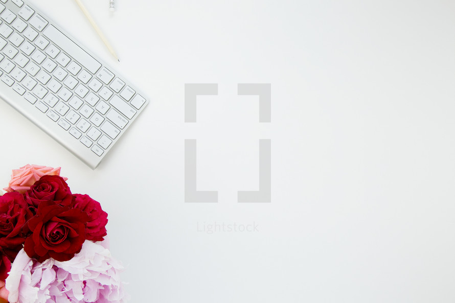 vase of flowers and computer keyboard border on white background 