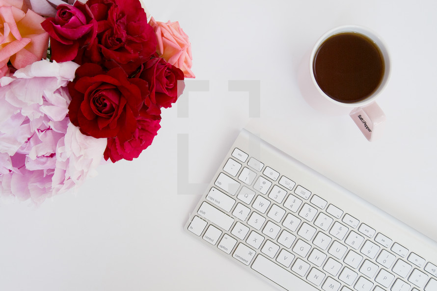 flowers, mug, and computer keyboard on a desk 