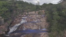 Drone hovers over water before flying backwards over waterfall