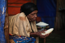 Elderly woman peeling corn
