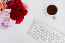 flowers, mug, and computer keyboard on a desk 