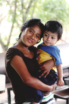 a smiling mother in Guatemala holding her toddler son 