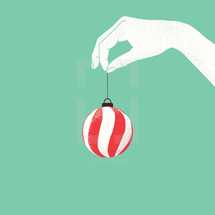hand holding out a striped Christmas ornament 